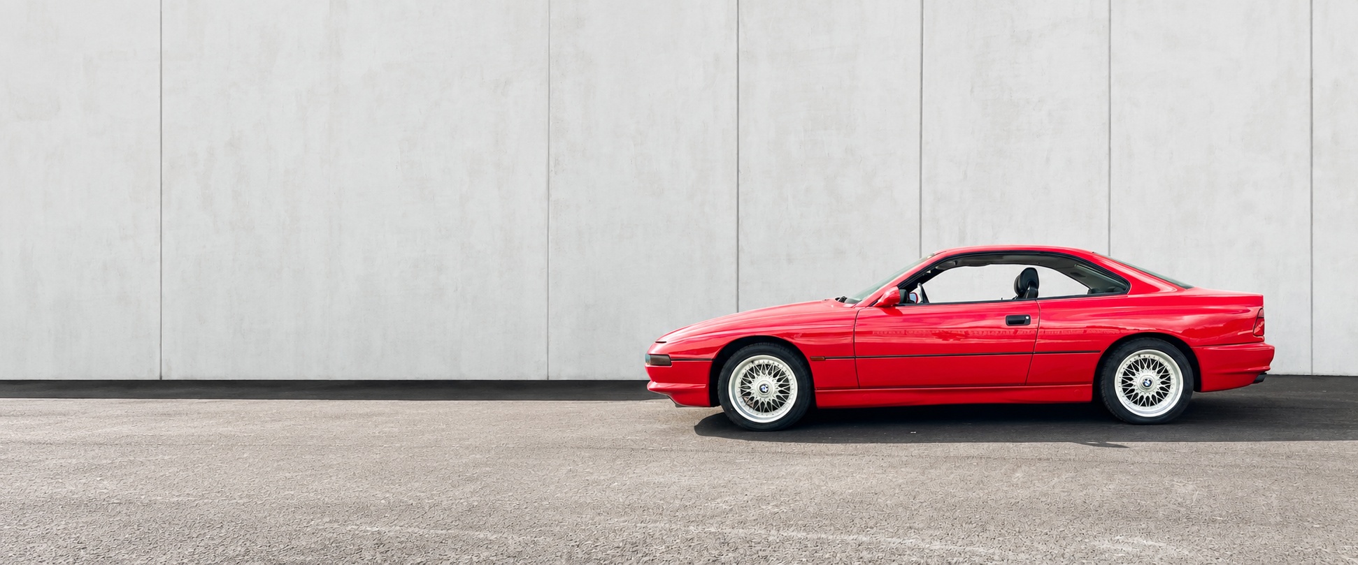 BMW 850 CSi (E31) vor grauer Betonwand