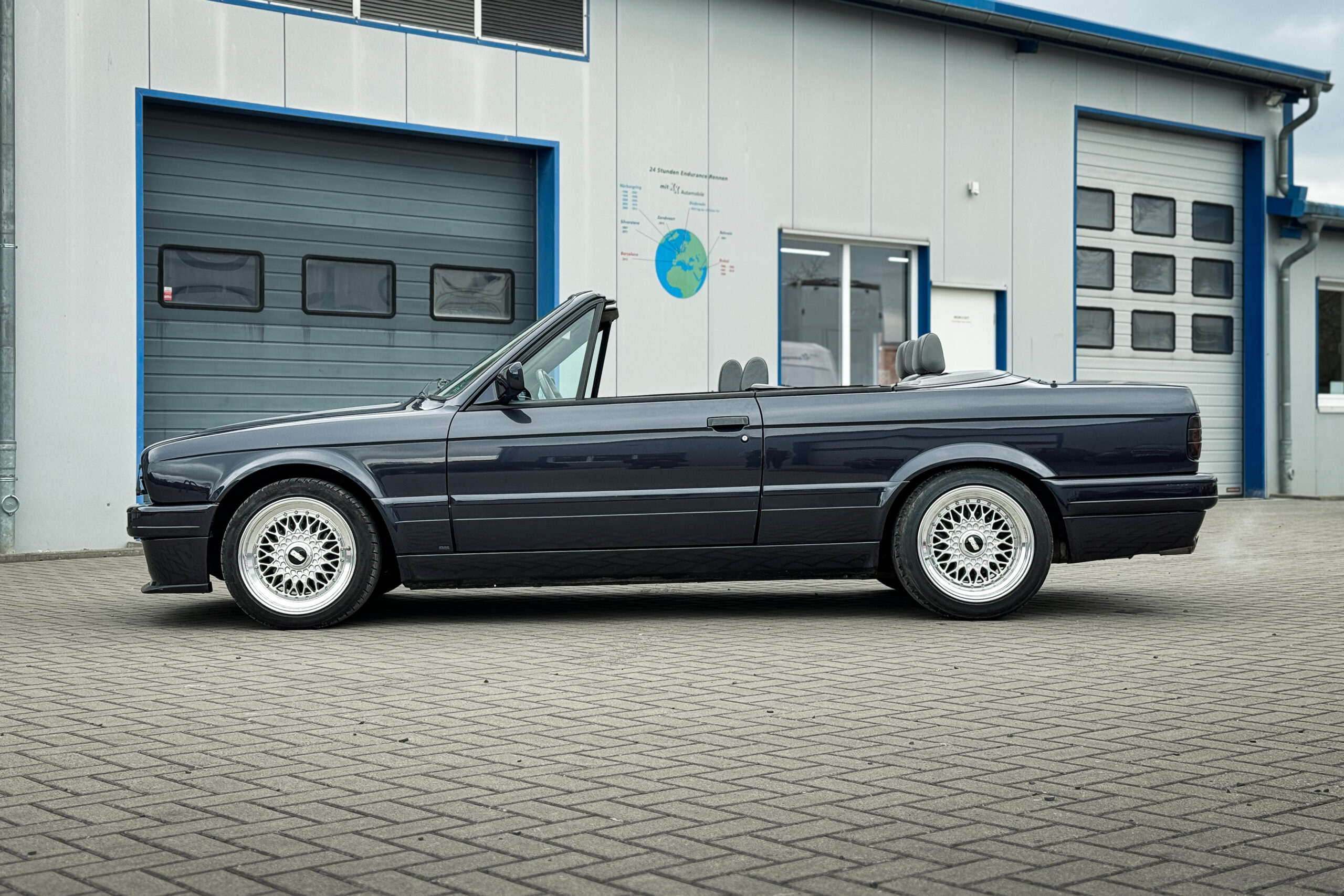 Dunkelblaues BMW 325i Cabrio der Baureihe E30 mit M-Technik-II-Paket in Seitenansicht