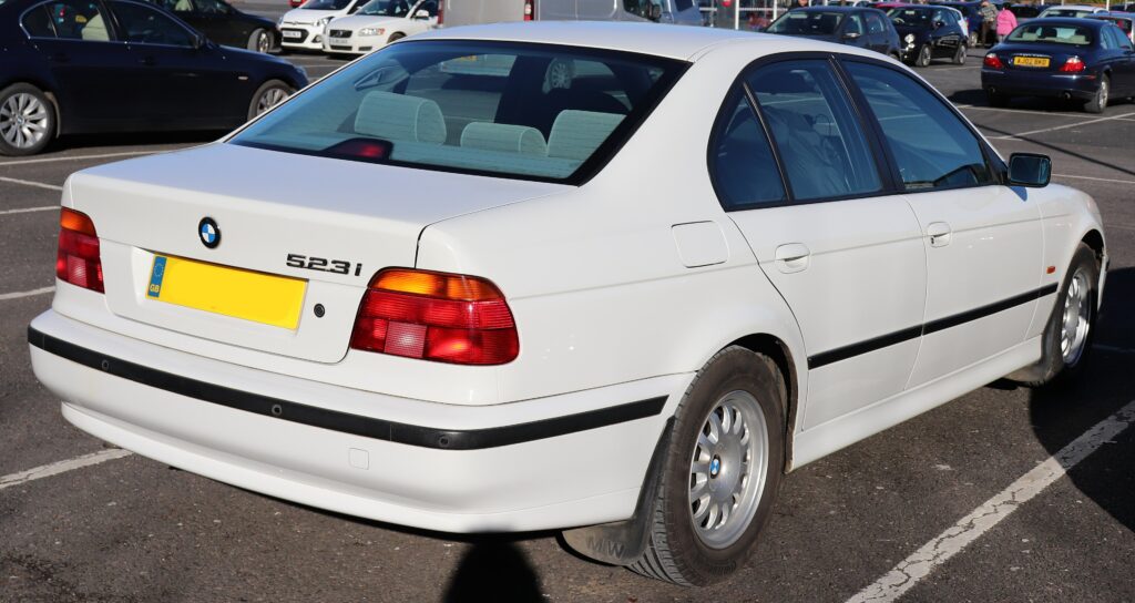 Weißer BMW 523i der Baureihe E39 von schräg hinten