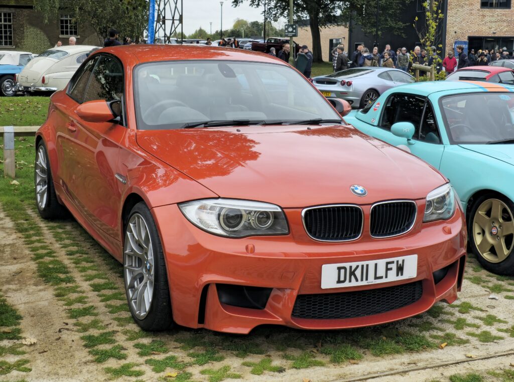 Orangefarbenes BMW 1er M Coupé in Dreiviertelansicht von vorn