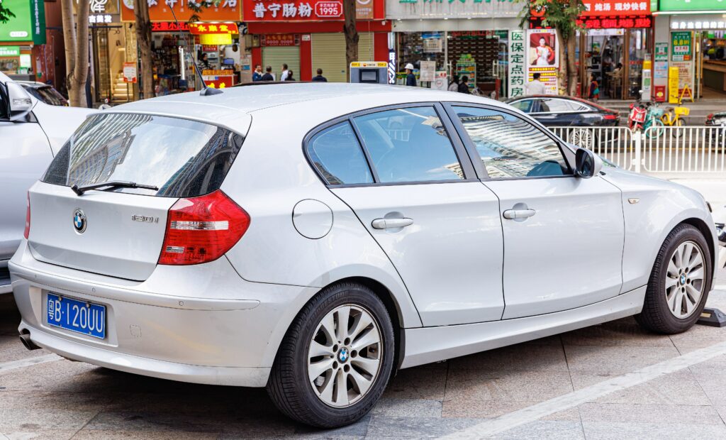 Weißer BMW 1er Fünftürer E87 von hinten links