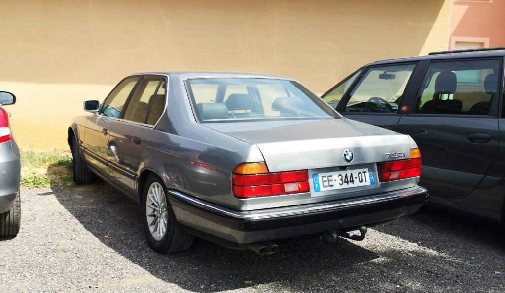 Dunkler BMW 730i der Baureihe E32 von schräg hinten