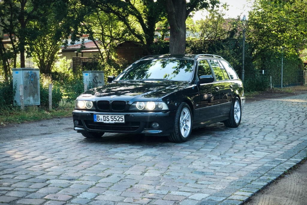 Schwarzer BMW 525i Touring E39 in der Totale auf Kopfsteinpflaster