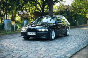Schwarzer BMW 525i Touring E39 in der Totale auf Kopfsteinpflaster