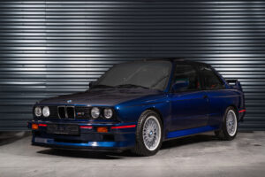 BMW M3 E30 Sport Evolution in Mauritiusblau (AC79200) — Dreiviertelansicht von vorn links, Heckflügel und BBS-Kreuzspeichenfelgen sichtbar