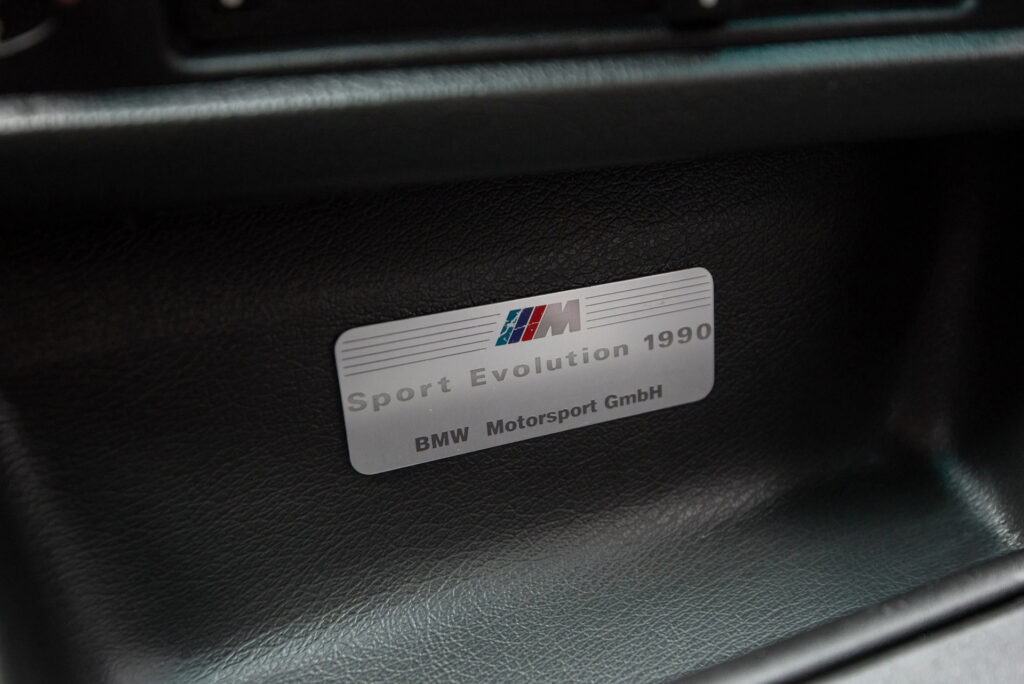 BMW M3 E30 Sport Evolution in Mauritiusblau (AC79200) — Plakette „Sport Evolution 1990 · BMW Motorsport GmbH" an der Mittelkonsole