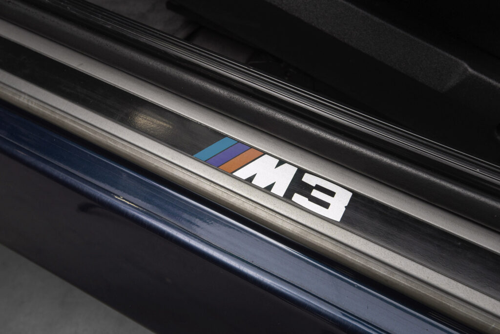 BMW M3 E30 Sport Evolution in Mauritiusblau (AC79200) — Einstiegsleiste mit M3-Emblem in der Fahrertür