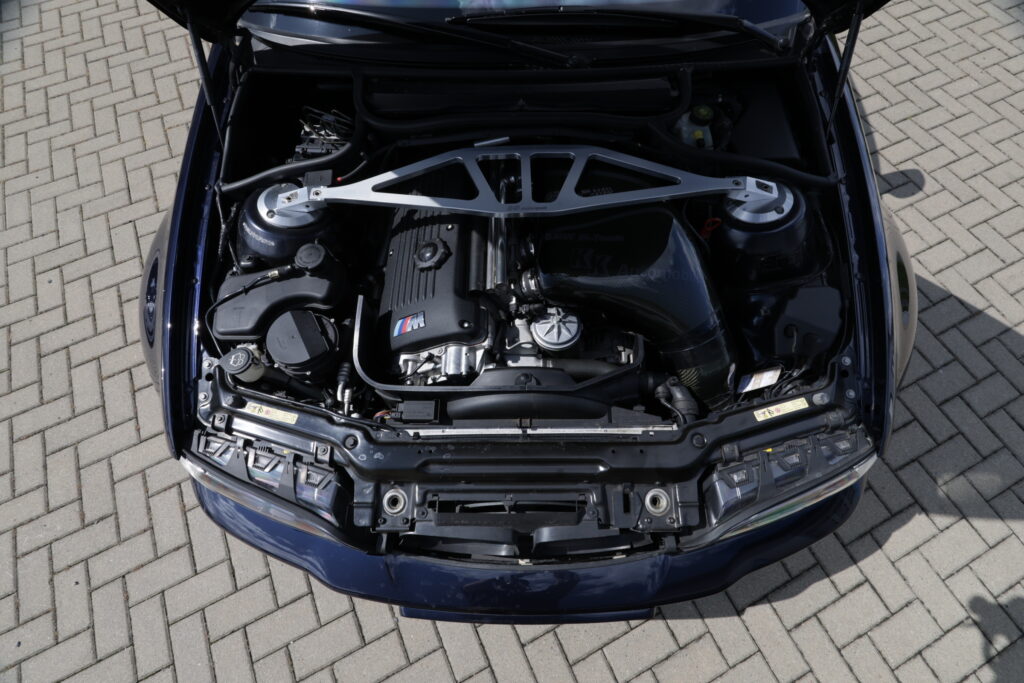 Motorraum eines BMW M3 E46 bei hartem Sonnenlicht, Motor im Schatten der Haube