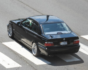 Schwarzes BMW 328i Coupé der Baureihe E36 in erhöhter Schrägansicht