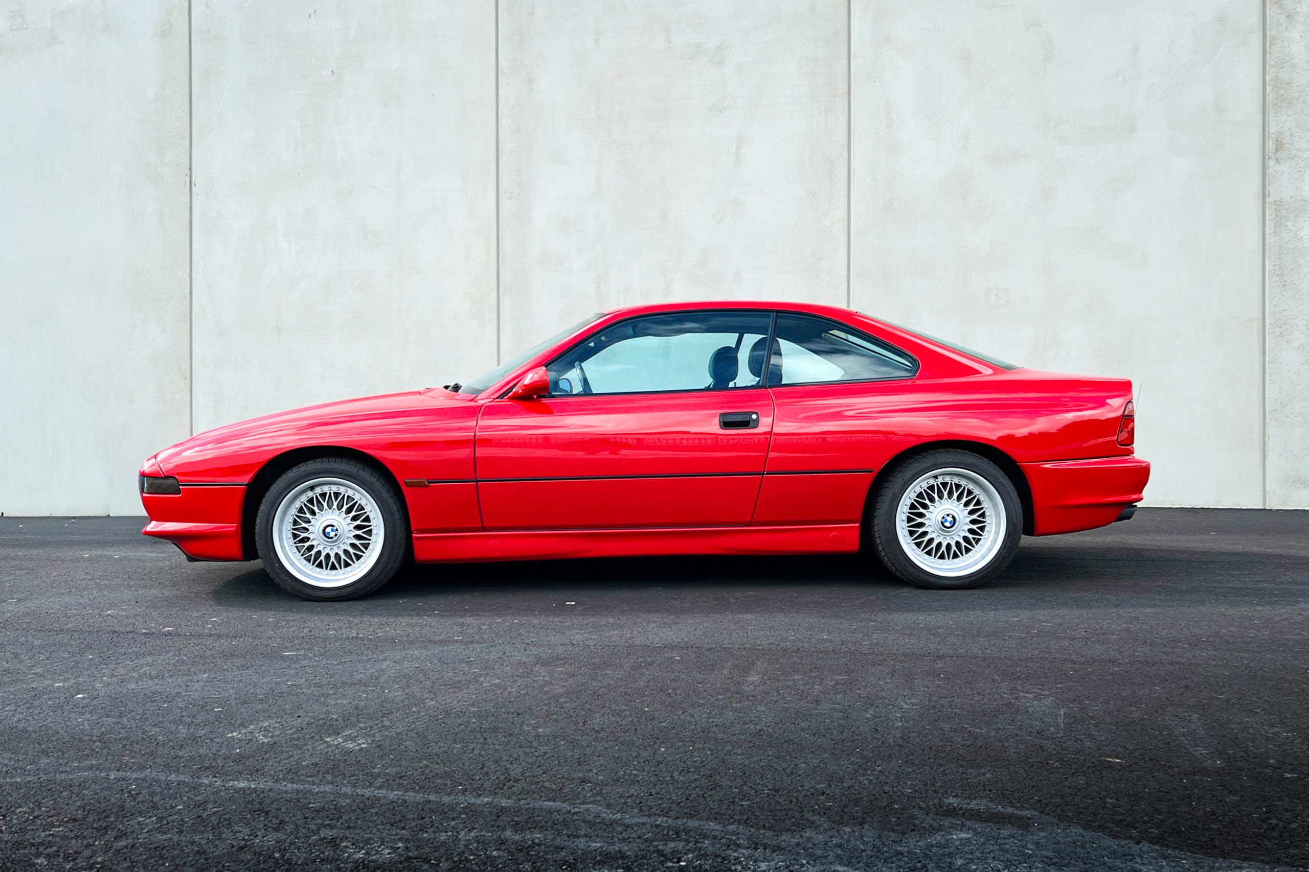 BMW 850Ci der Baureihe E31 in Rot, Seitenansicht vor einer Betonwand