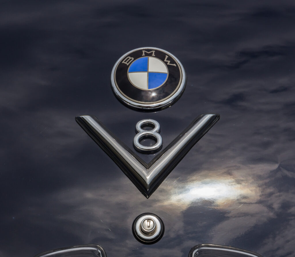 BMW-Emblem und V8-Schriftzug auf dunkelblauer Motorhaube eines BMW 502