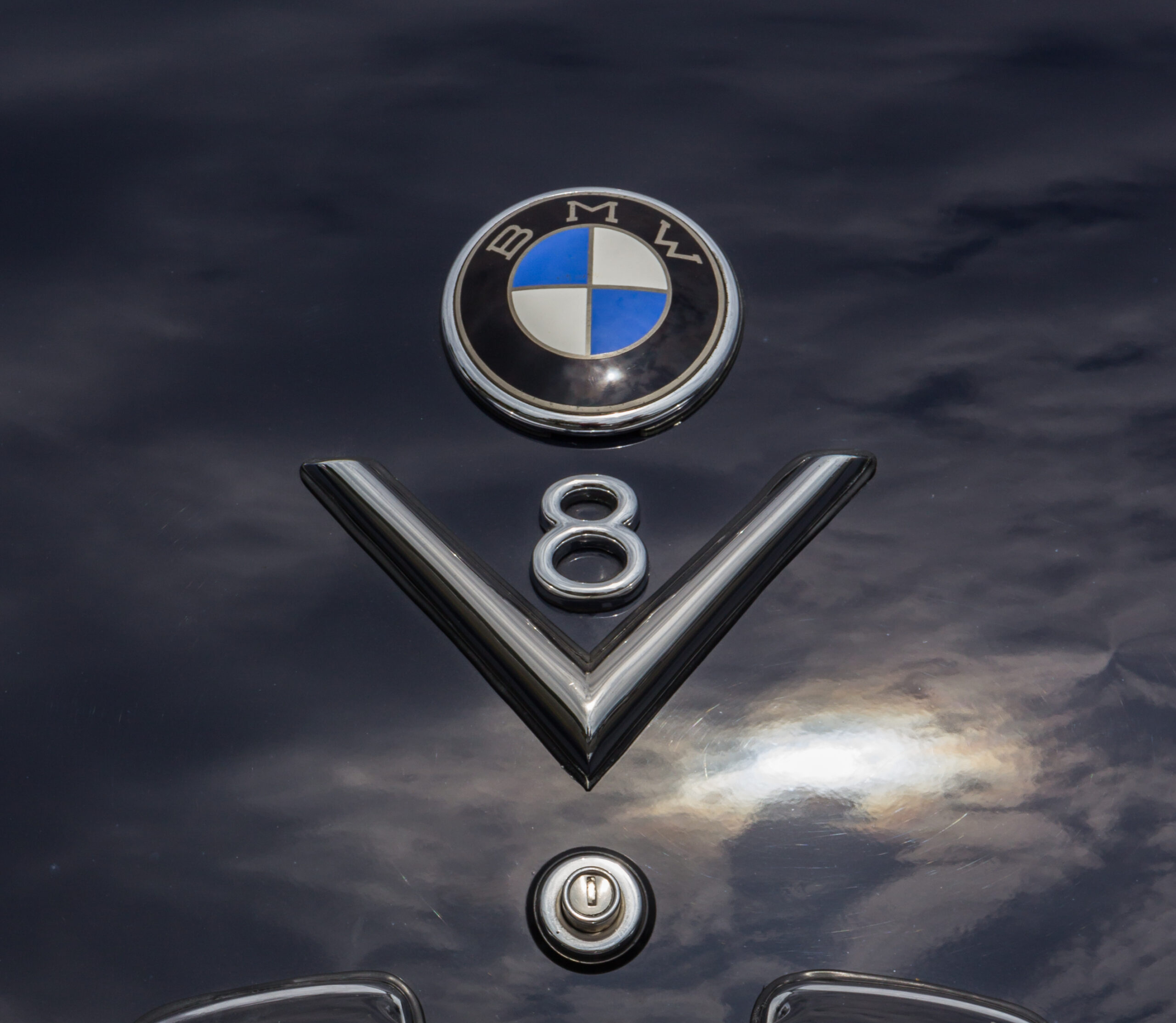 BMW-Emblem und V8-Schriftzug auf dunkelblauer Motorhaube eines BMW 502