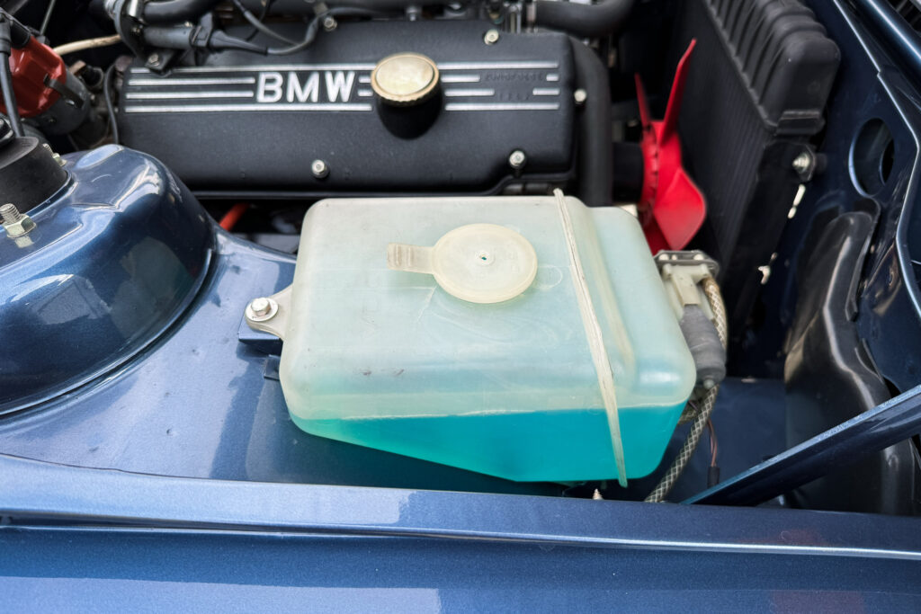 Ausgleichsbehälter und Ventildeckel im Motorraum eines BMW 320i der Baureihe E21