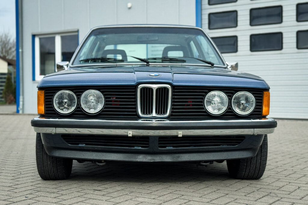 Frontansicht eines BMW 320i der Baureihe E21 mit vier Rundscheinwerfern