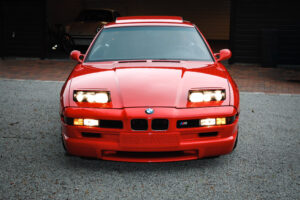 Front eines hellroten BMW 850CSi mit ausgefahrenen Klappscheinwerfern