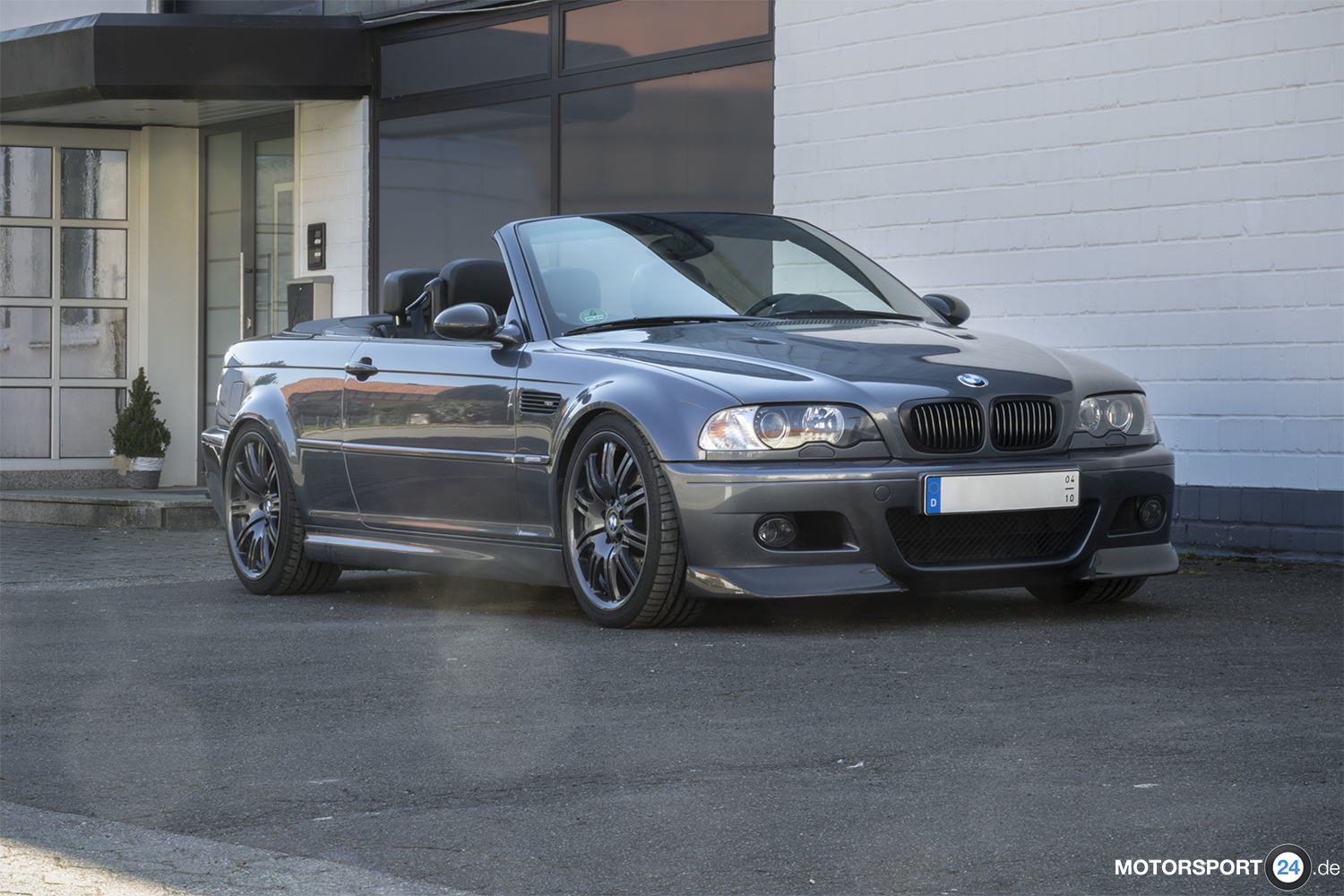 Front-Seitenansicht des offenen BMW M3 E46 Cabrio vor einer weißen Halle