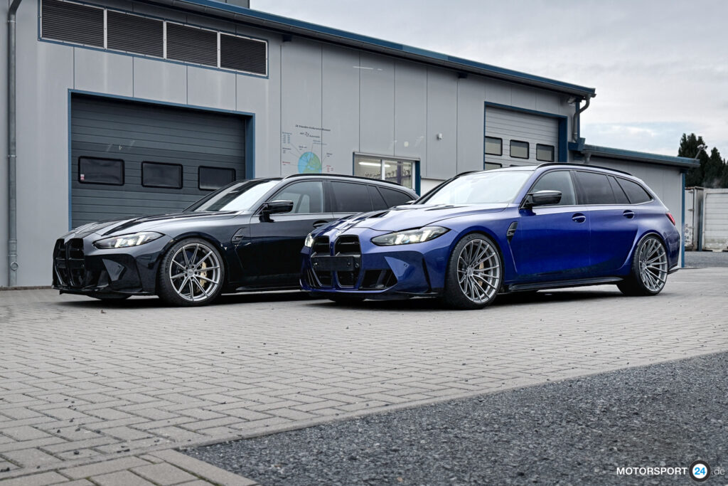 Zwei BMW M3 Touring der Baureihe G81 in Schwarz und Blau nebeneinander vor einer Werkstatthalle