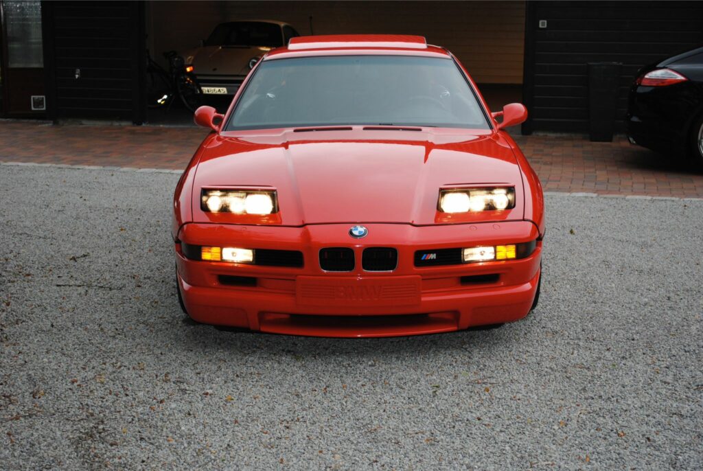 Front eines hellroten BMW 850CSi mit ausgefahrenen Klappscheinwerfern