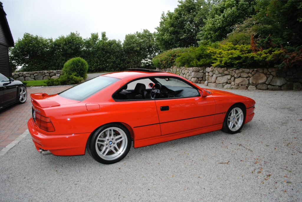 Hellroter BMW 850CSi in der Seitenansicht von hinten rechts