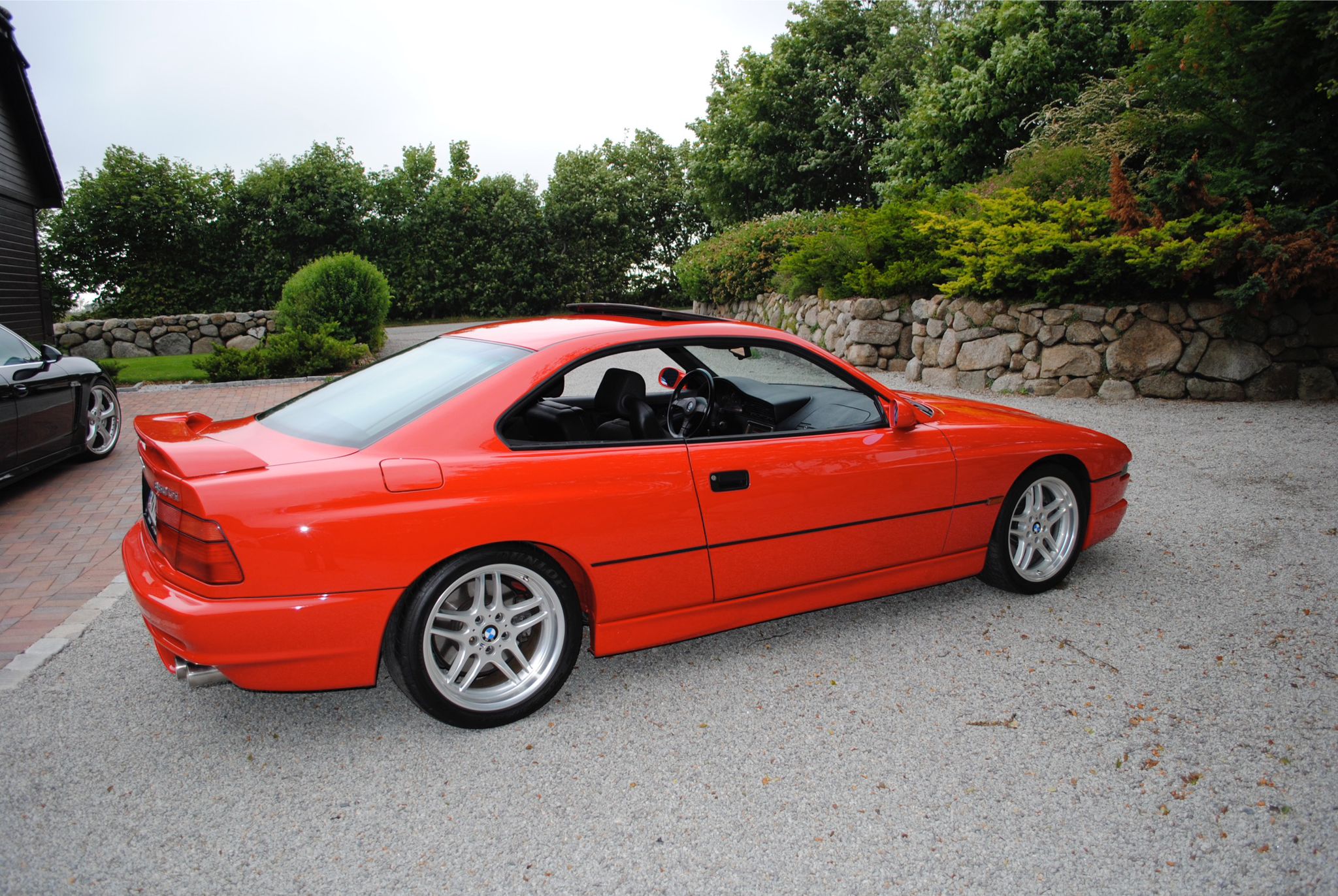 Hellroter BMW 850CSi in der Seitenansicht von hinten rechts